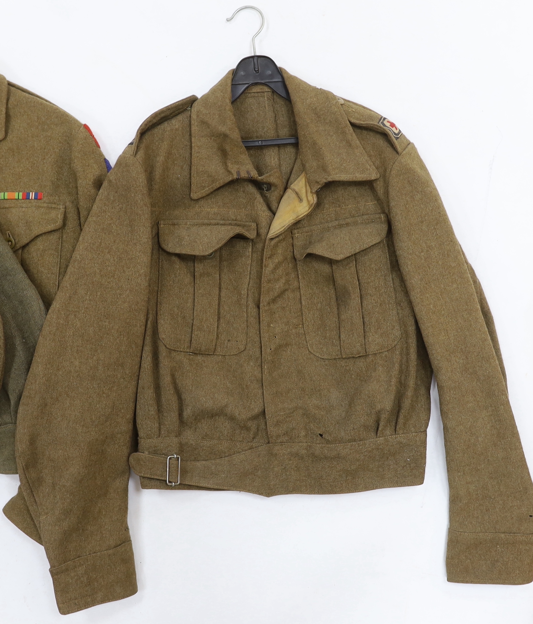 Eight British military uniform blouses/jackets, including two with Royal Sussex Regiment Cinque Ports shoulder insignia, a Queen’s A.C.F. example, etc.